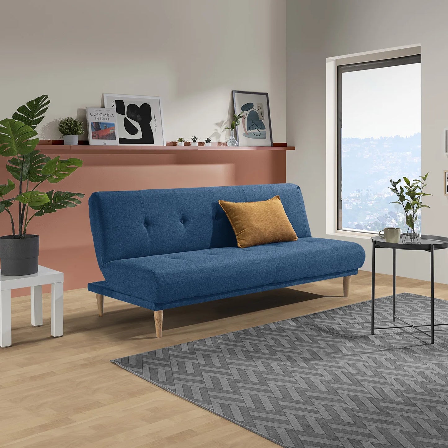 Sofá cama Arena en tela azul con cojín ocre, patas en madera tono natural, ubicado en sala moderna con decoración minimalista, ideal para apartamentos y casas de familias colombianas - All Star Muebles Colombia