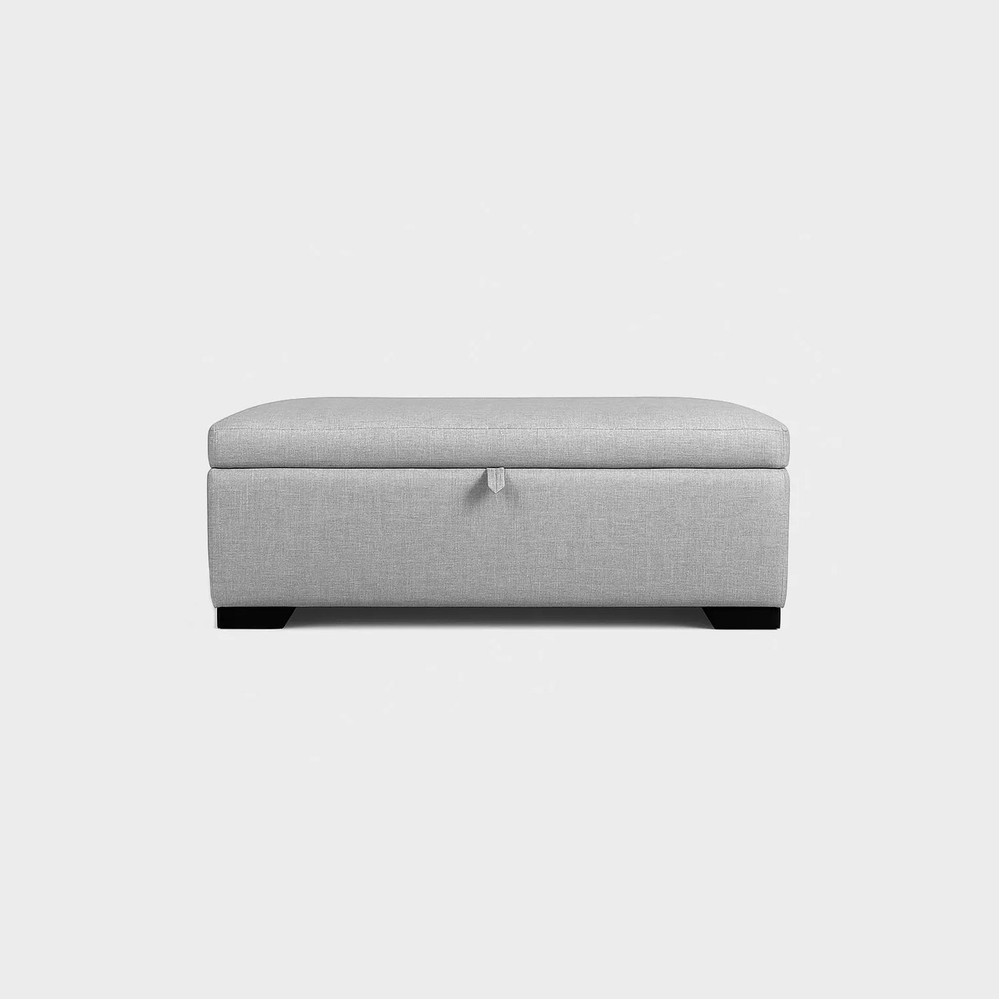 Puff tipo baúl visto de frente, tapizado color gris, con patas en madera color negro, fotografía sobre fondo blanco, ideal para visualizar la combinación de estilos y colores - All Star muebles