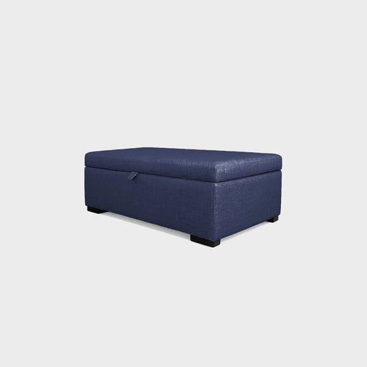 Puff tipo baúl visto en perspectiva, tapizado color azul, con patas en madera color negro, fotografía sobre fondo blanco, ideal para visualizar la combinación de estilos y colores - All Star muebles