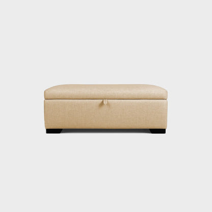 Puff tipo baúl visto de frente, tapizado color beige, con patas en madera color negro, fotografía sobre fondo blanco, ideal para visualizar la combinación de estilos y colores - All Star muebles
