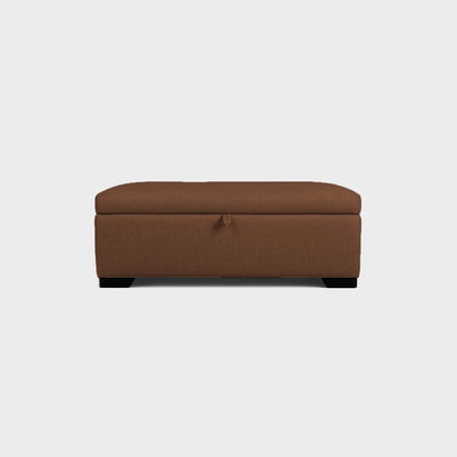 Puff tipo baúl visto de frente, tapizado color café, con patas en madera color negro, fotografía sobre fondo blanco, ideal para visualizar la combinación de estilos y colores - All Star muebles