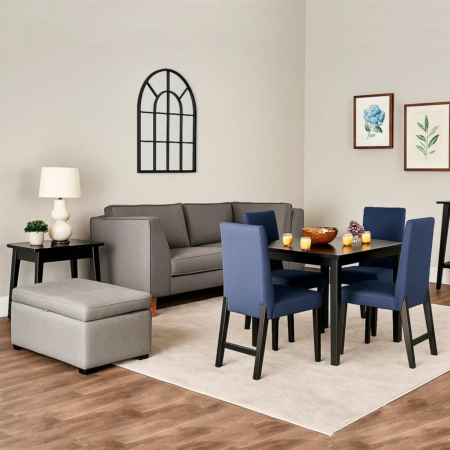 Sofá 3 puestos en tela gris con patas en madera color natural, ubicado en sala moderna con puff tipo baúl color gris, ambientado con comedor de madera en tono negro y sillas tapizadas color azul. Ideal para hogares colombianos que buscan confort y estilo moderno - All Star muebles